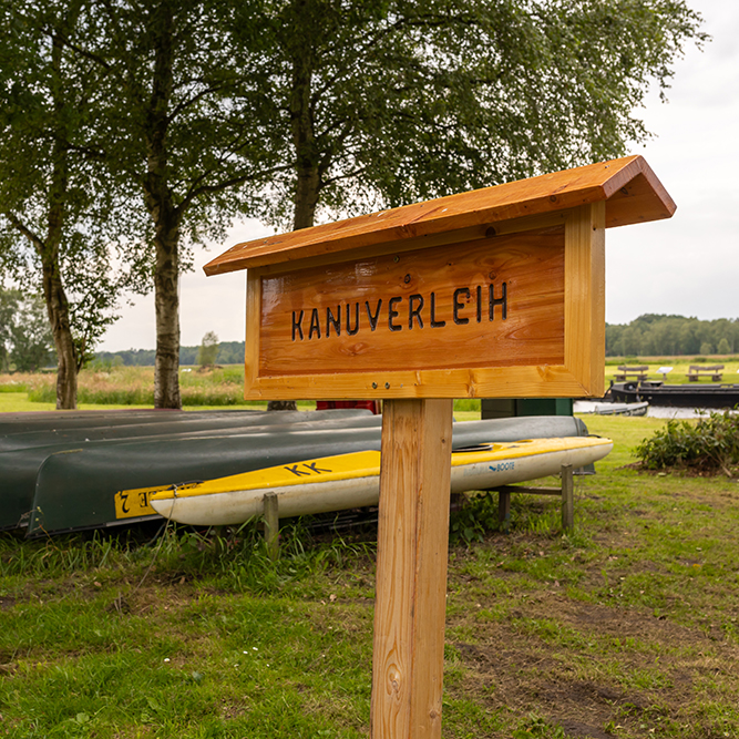 Infoschild für Kanutouren am Torfschiffhafen und Kanus im Hintergrund