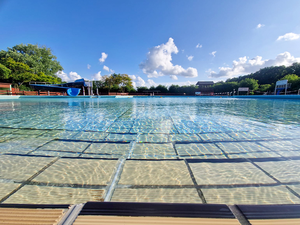 Wasserbecken des Freibad Waldbad Gnarrenburg. Im Hintergrund die große Wasserrutsche und der Sprungturm.